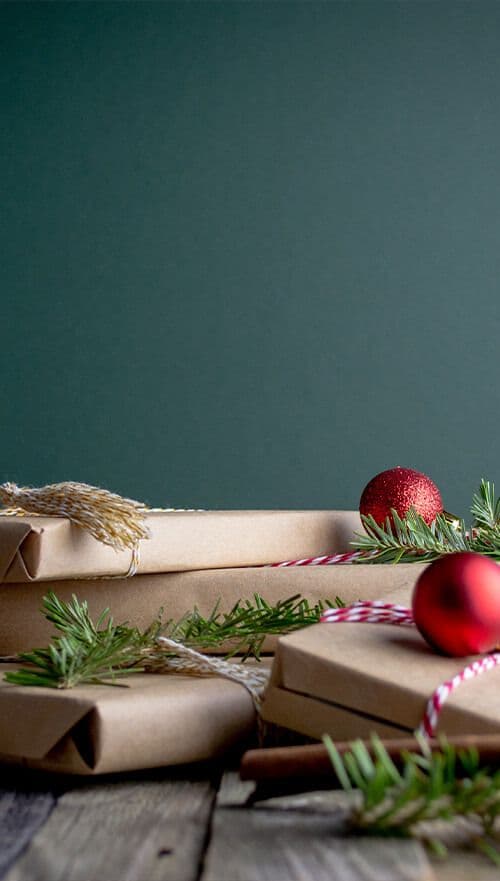 Weihnachtsgeschenke auf einem Tisch vor einer grünen Wand
