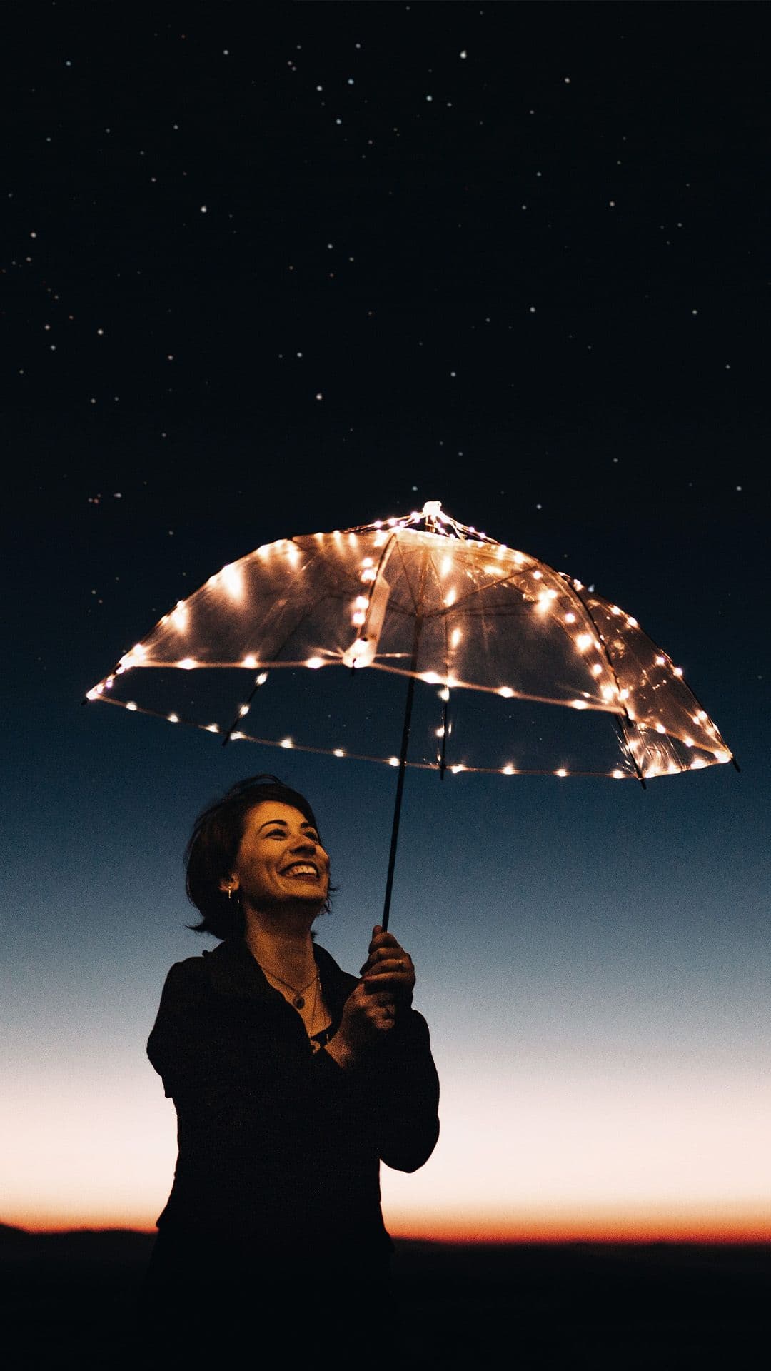 Lächelnde Frau hält einen LED-Regenschirm in der Hand